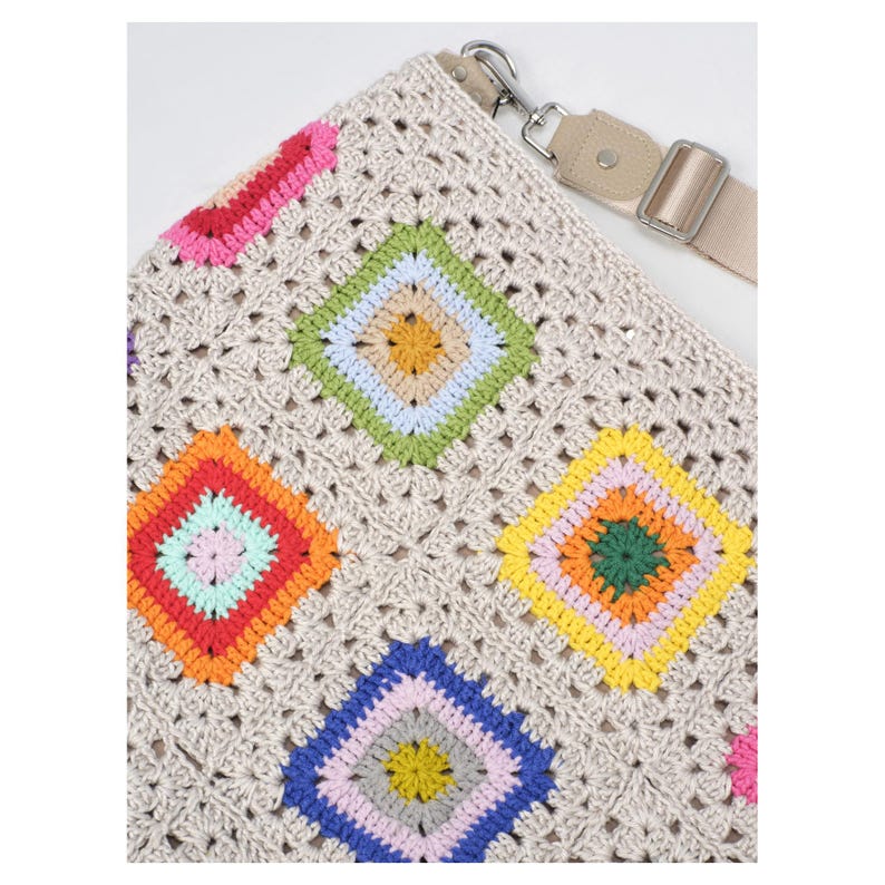 K&ouml;nnte beinhalten: Beige H&auml;keltasche mit farbenfrohem Rautenmuster. Die Rauten sind in den Farbt&ouml;nen Rosa, Rot, Orange, Gelb, Gr&uuml;n und Blau gehalten. Die Tasche hat einen verstellbaren beigen Riemen und silberfarbene Hardware.
