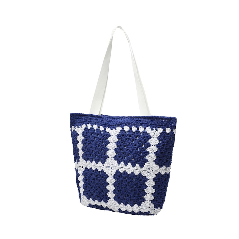 May include: A blue and white crochet tote bag with white handles. The bag features a geometric pattern of white squares against a dark blue background. The handles are made of a smooth, white material.