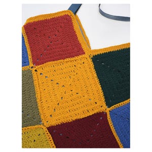 Puede incluir: Un bolso tote de crochet colorido con un dise&ntilde;o de patchwork. El bolso est&aacute; hecho de cuadrados en varios colores, incluyendo rojo, amarillo, verde y azul. Tiene una correa azul oscuro.