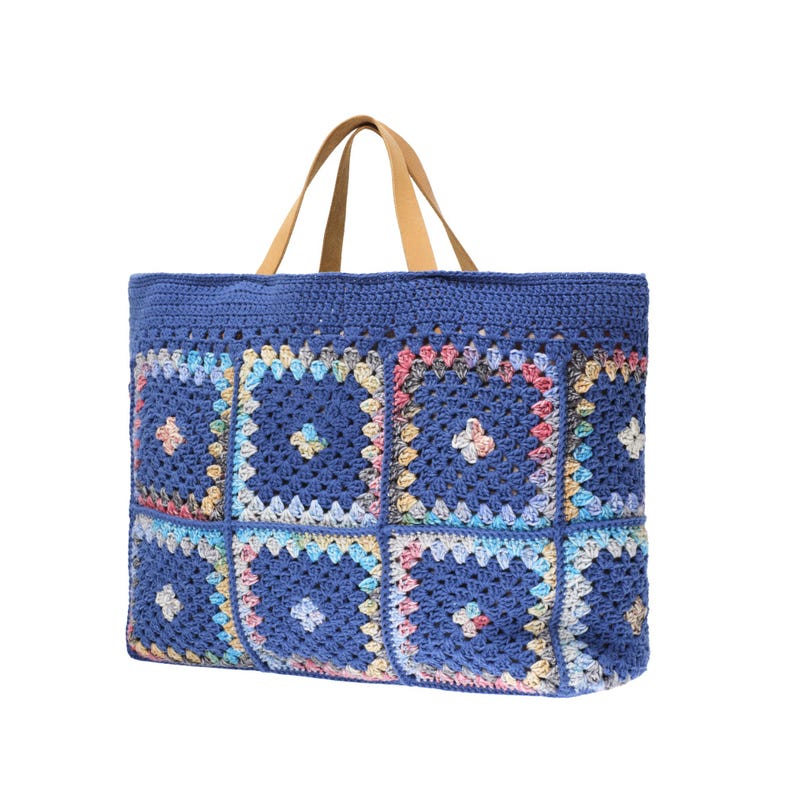 Puede incluir: Un bolso tote de crochet azul con un dise&ntilde;o de patchwork. La bolsa presenta una serie de cuadrados coloridos con detalles florales. Tiene asas de cuero marr&oacute;n y un interior espacioso, perfecto para llevar lo esencial.