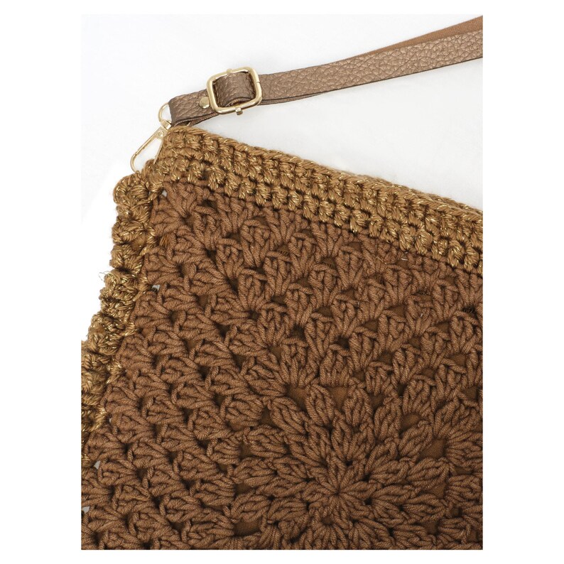 May include: A brown crochet bag featuring a detailed floral-inspired pattern with a textured surface. The bag includes a metallic gold-toned border along the top edge and a thin, adjustable brown strap attached with a gold-colored metal buckle.