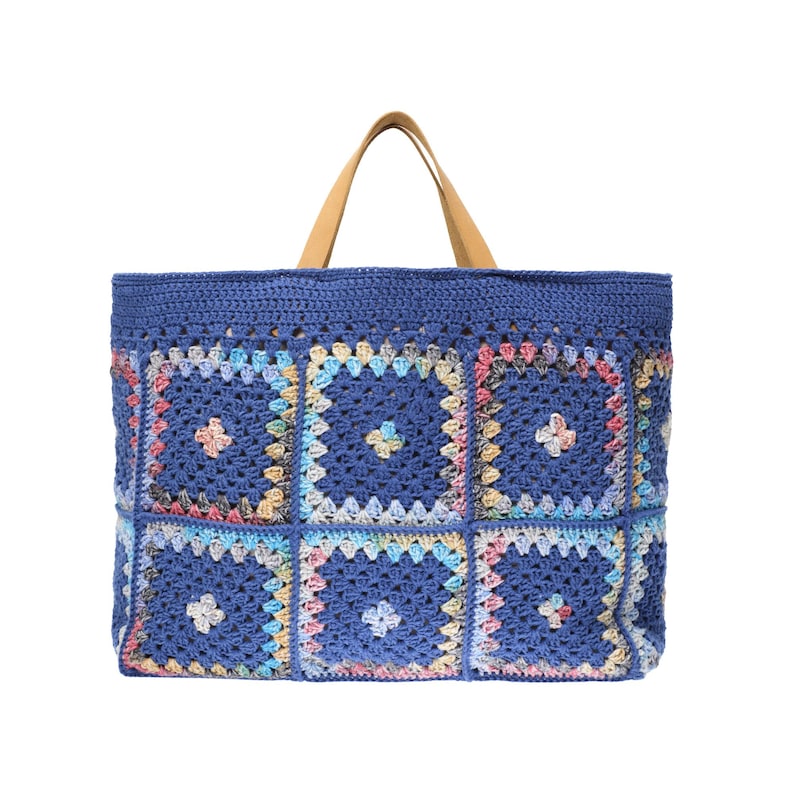 Puede incluir: Un bolso tote de crochet azul con un dise&ntilde;o de patchwork. El bolso presenta una parte superior e inferior azul liso, con una serie de parches cuadrados de colores. El bolso tiene dos asas de cuero marr&oacute;n.