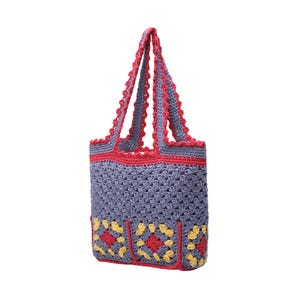 May include: A handmade crochet tote bag in a gray-blue hue, accented with red trim and handles. The bag features a detailed stitch pattern and decorative yellow and red squares at the base. This stylish bag is perfect for carrying groceries or personal items.