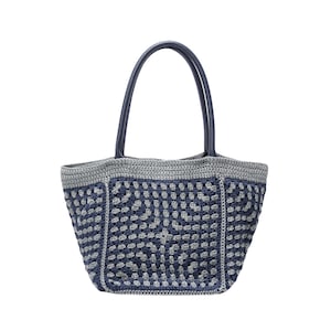 May include: A crocheted tote bag in blue and grey with a geometric pattern. It has dark blue leather handles. The bag is designed for carrying items. The bag's dimensions are approximately 30 cm in width and 30 cm in height.
