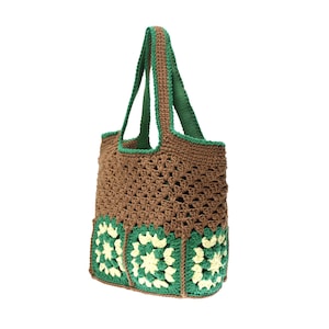 K&ouml;nnte beinhalten: Eine geh&auml;kelte Tragetasche in Braun und Gr&uuml;n. Die Tasche hat einen braunen K&ouml;rper mit gr&uuml;nen Verzierungen und Griffen. Der Boden der Tasche hat gr&uuml;ne und cremefarbene Blumenquadrate. Die Tasche ist aus weichem, strukturiertem Garn gefertigt.