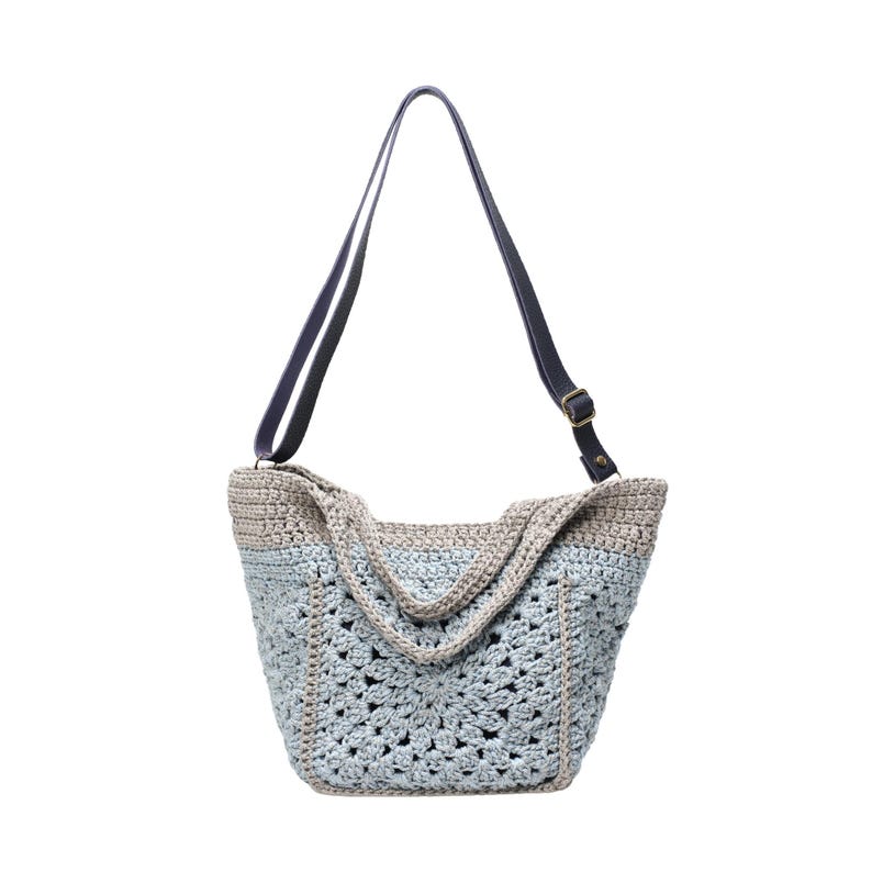May include: A crocheted tote bag with a light blue and beige color scheme. The bag features a geometric pattern and a dark blue shoulder strap with a brass buckle. The bag is designed with a wide opening and a sturdy construction.