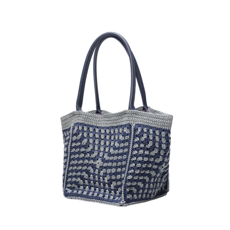 May include: A handmade tote bag with a blue and grey crochet pattern. The bag features a geometric design and has dark blue leather handles. The top edge and handles are a darker shade of blue.