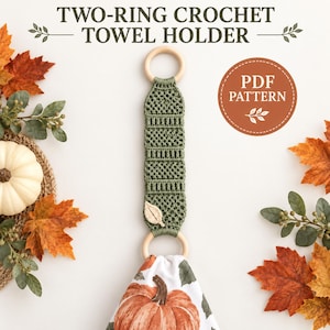 Pode incluir: Um suporte de toalha de crochê com dois anéis, apresentando uma tira de crochê texturizada em verde sálvia com uma pequena aplicação de folha cor de creme, conectada a dois anéis de madeira clara. O texto diz TWO-RING CROCHET TOWEL HOLDER e PDF PATTERN.