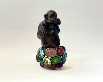 Vintage Iradj Moini monkey brooch, with carved monkey figure atop colorful stones and gold toned double pin