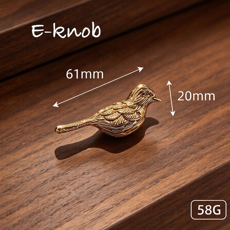 May include: A gold-colored bird-shaped knob labeled E-knob. The bird features detailed wing and feather engravings. Dimension arrows indicate a length of 61mm and a height of 20mm. The object is marked with a weight of 58G.