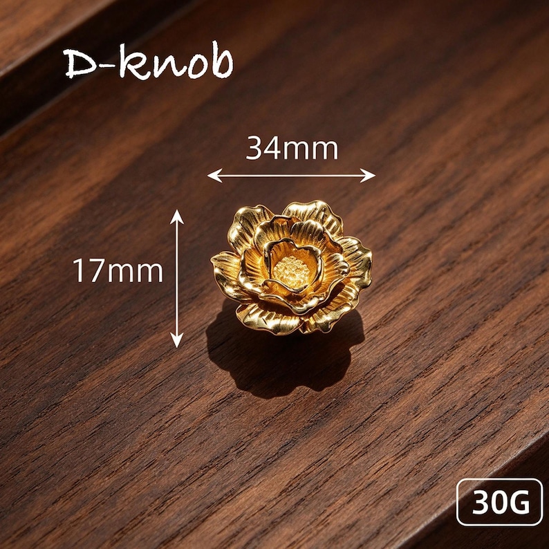 May include: A gold-colored flower-shaped D-knob with a textured center and layered petals. The knob measures 34mm in width and 17mm in height, with a weight of 30G. The design features a metallic finish with detailed petal contours.