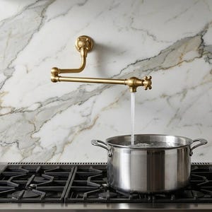 Può includere: Un rubinetto riempitore per pentole in ottone montato a parete con braccio snodato doppio e manopole a croce. L'acqua scorre dal beccuccio in una grande pentola in acciaio inossidabile posizionata su un piano cottura a gas nero con griglie.