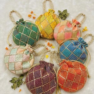 May include: A collection of seven round, beaded drawstring pouches in various colors, including green, yellow, pink, blue, and orange. Each pouch features a grid pattern and a beaded handle. The pouches are arranged on a white surface.