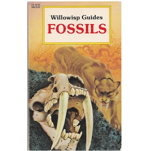 May include: A paperback book titled Willowisp Guides FOSSILS featuring a cover illustration of a saber-toothed cat skull in the foreground and a living saber-toothed cat in the background against an orange and yellow landscape.