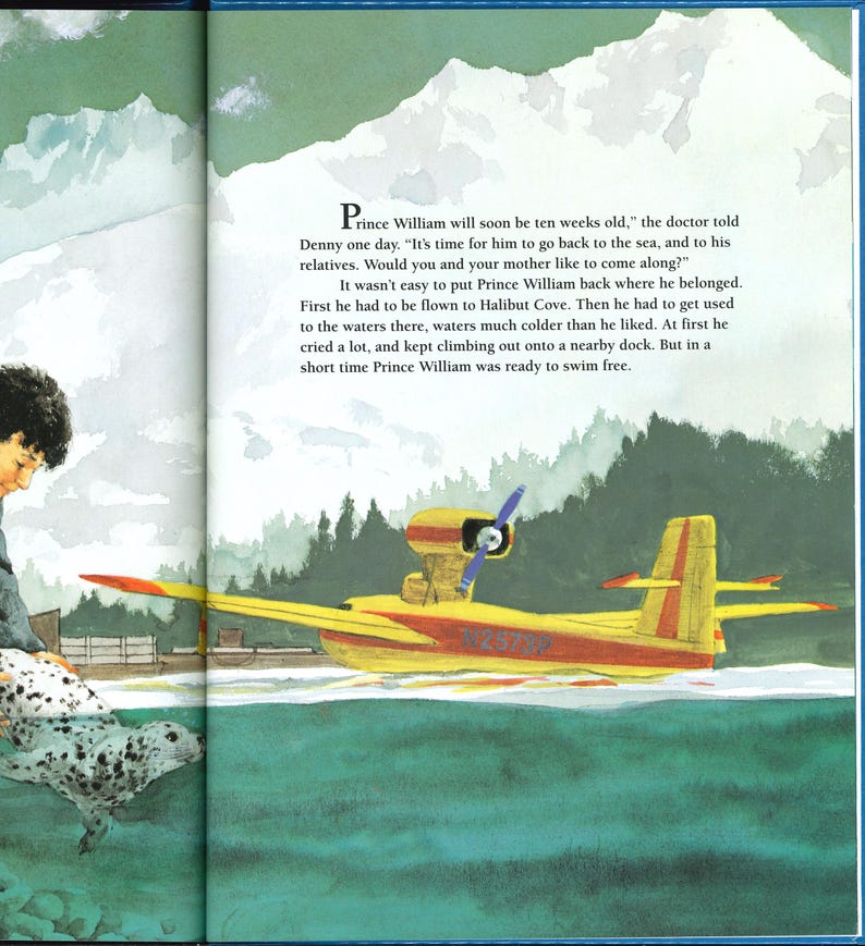 May include: Illustration from a children's book featuring a yellow seaplane with red accents on the water. The text reads "Prince William will soon be ten weeks old." A seal and a person are also visible.