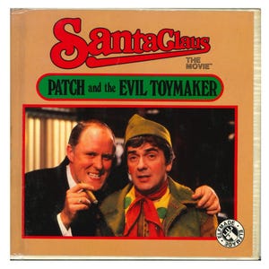 May include: A vintage movie cover for "Santa Claus: The Movie" featuring the text "PATCH and the EVIL TOYMAKER." The cover has a tan background with red and green text. Two men are pictured, one holding a cigar.