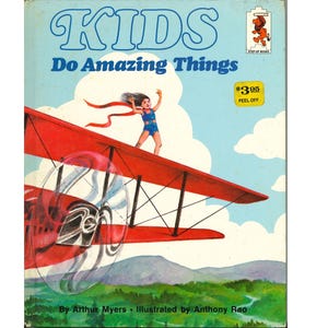 May include: Vintage book cover titled "KIDS Do Amazing Things." The illustration shows a child standing on a red biplane wing against a blue sky. The book has a peel-off price tag.