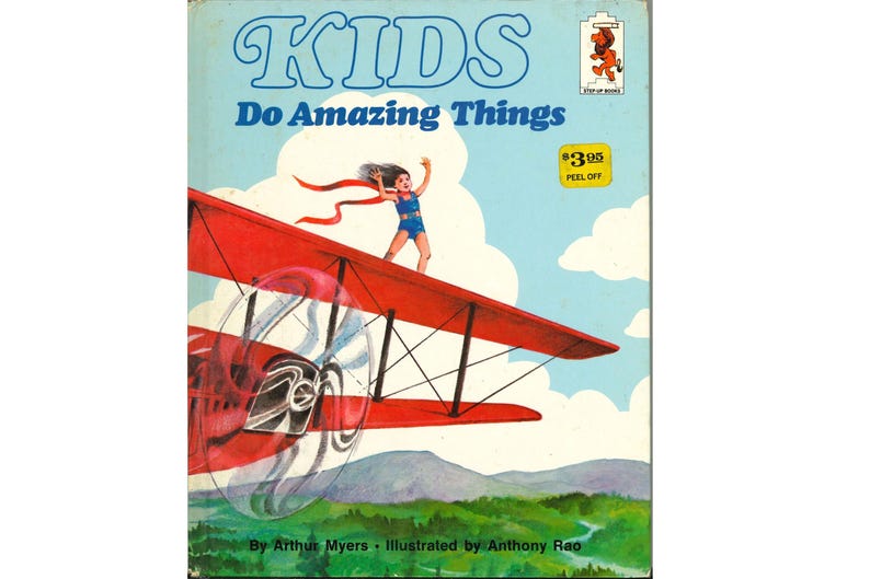 May include: Vintage book cover titled "KIDS Do Amazing Things." The illustration shows a child standing on a red biplane wing against a blue sky. The book has a peel-off price tag.