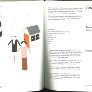May include: An open book page with illustrations of paper houses and figures. The houses have gray roofs, black windows, and orange doors. The figures are made of paper tubes with simple facial features and clothing. Text on the right side reads "FUN CITY" and "Town and Buildings".