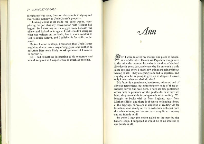 May include: Open book with text on both pages. The left page has the title "A NUGGET OF GOLD" and text. The right page has the name "Ann" in cursive and more text. The book is open to a chapter.