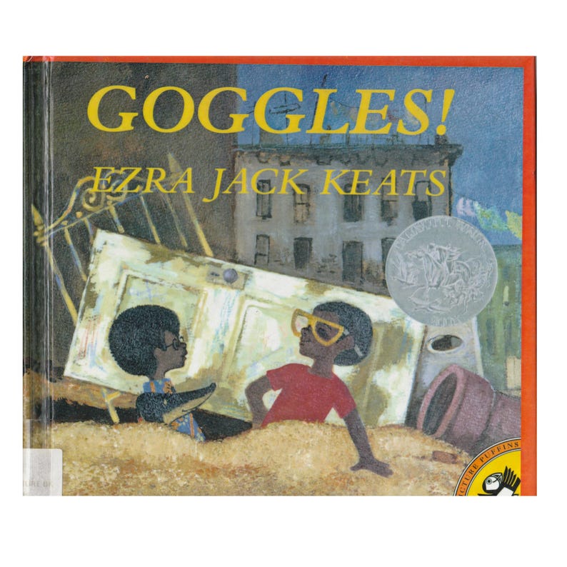K&ouml;nnte beinhalten: Ein Buchcover mit dem Titel "GOGGLES!" von Ezra Jack Keats. Das Cover zeigt zwei junge schwarze Jungen, die eine Brille tragen, einer in Rot und einer in Blau, die vor einer gro&szlig;en, umgefallenen T&uuml;r stehen.