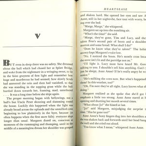 May include: Open book with text on cream-colored pages. The left page has a large letter "V" and a paragraph beginning with "But." The right page has text and the title "HEARTSEASE" at the top. The book is open to pages 98 and 99.