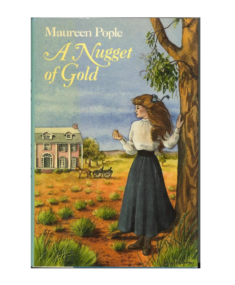 May include: Book cover illustration for "A Nugget of Gold" by Maureen Pople. The cover features a woman in a white blouse and long blue skirt standing near a tree. A pink house and a horse-drawn carriage are in the background. The title is in gold script.