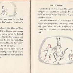 May include: A black and white illustration of a kangaroo, a cat, and a girl. The kangaroo is standing on its hind legs and holding a small cat in its arms. The girl is wearing a red dress and is holding a small cat in her arms. The text "LILY'S LOST!" is written at the top of the page.