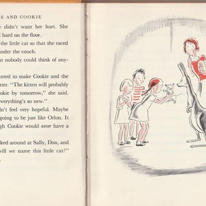 May include: A black and white illustration of a kangaroo with a small kitten in its pouch. A woman and three children are standing in front of the kangaroo. The text "Evie and Cookie" is at the top of the page.