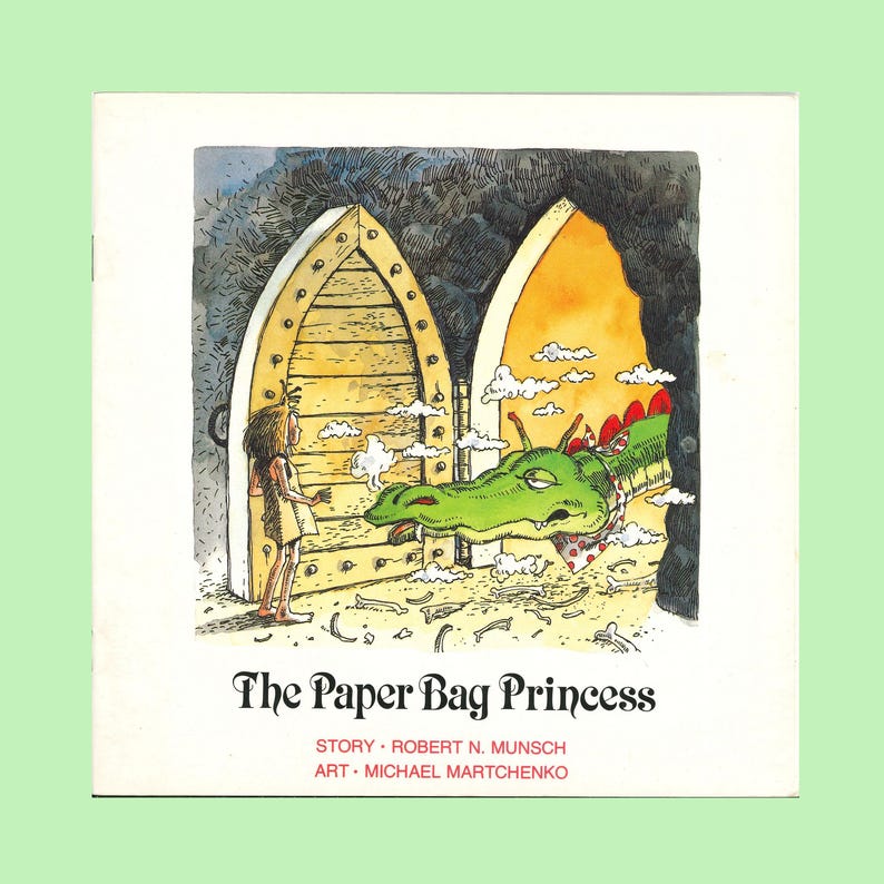 May include: A children's book titled The Paper Bag Princess with a story by Robert N. Munsch and art by Michael Martchenko. The cover illustration depicts a character standing before a large wooden door with a green dragon emerging from a cave.