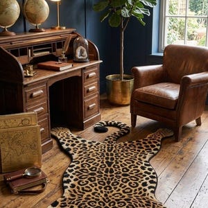 May include: A leopard-shaped area rug featuring a realistic spotted pattern in shades of tan, brown, and black, with green eyes on the feline head. The rug is laid flat on a wooden floor, showcasing a detailed animal silhouette with four paws.