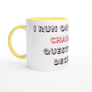 Op de afbeelding: Witte keramische mok met een gele handgreep en binnenkant. De mok heeft de tekst "I RUN ON CHAOS, QUESTIONS, DECISIONS" in zwarte en rode letters. Een humoristisch en motiverend item.