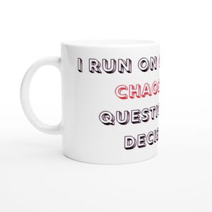 Op de afbeelding: Witte keramische mok met de tekst "I RUN ON CHAOS, QUESTIONS, DECISIONS" in zwarte en rode letters. De mok heeft een gebogen handvat en staat tegen een witte achtergrond.