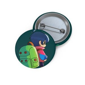 Peut inclure: Deux badges ronds et verts. L'un d'eux représente un personnage de dessin animé avec un sac à dos vert et une veste rose et bleue. L'autre badge est un dos d'épingle argenté.