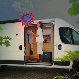 Puede incluir: Una furgoneta camper blanca con la puerta lateral abierta que revela un interior de madera. Una persona está de pie dentro de la furgoneta, mirando hacia arriba a un objeto flotante en forma de estrella con un patrón hipnótico azul y rojo.