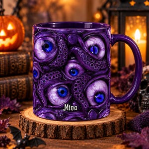 Peut inclure: Un mug en céramique violette orné d'un motif graphique détaillé représentant plusieurs créatures aux yeux bleus et des tentacules. Le nom Mina est imprimé en lettres gothiques blanches près de la base du mug. L'anse est violette.