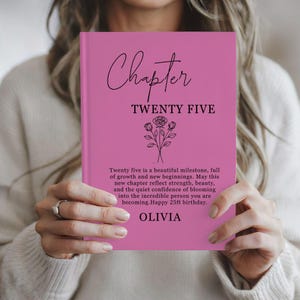 May include: A bright pink hardcover book featuring black text that reads Chapter TWENTY FIVE, followed by a line drawing of three roses. Below the flowers, a paragraph of text celebrates a 25th birthday, ending with the name OLIVIA.