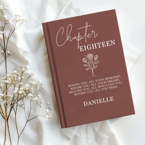 May include: A terracotta-colored hardcover book featuring the white text Chapter EIGHTEEN, a line-art illustration of three roses, and the quote: BEHIND YOU, ALL YOUR MEMORIES, BEFORE YOU, ALL YOUR DREAMS, AROUND YOU, ALL WHO LOVE YOU, WITHIN YOU, ALL YOU NEED. DANIELLE.