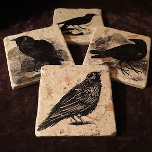 May include: Set of four square coasters featuring black and white illustrations of crows on a beige background. The coasters are made of natural stone.