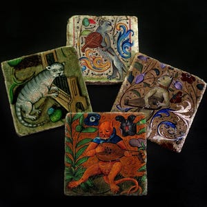 May include: Four square stone coasters featuring colorful illustrations of anthropomorphic cats playing musical instruments, including a lute, a violin, and a keyboard, surrounded by intricate floral and vine patterns in various shades.