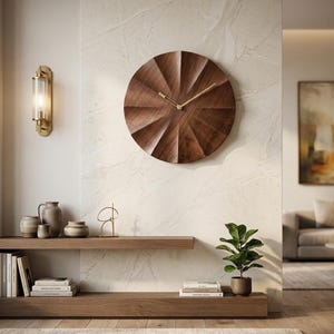 Pode incluir: Um relógio de parede circular feito de madeira castanha escura com uma textura facetada semelhante a um sol. O relógio apresenta ponteiros de metal dourado para as horas e os minutos centrados no mostrador. O design é simples, sem números.