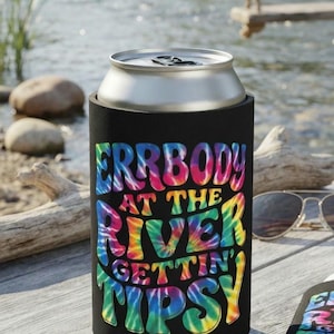 May include: A black foam can cooler featuring a tie-dye pattern in shades of blue, pink, yellow, and green. The text printed on the front reads "ERRBODY AT THE RIVER GETTIN' TIPSY" in a bold, stylized font. The cooler is cylindrical and holds a metal can.