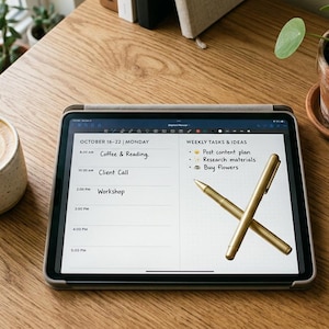 Könnte beinhalten: Ein Holztisch mit einem Latte Macchiato in einer gesprenkelten Tasse, einem Tablet mit einem Zeitplan und zwei goldenen Stiften. Das Tablet zeigt eine wöchentliche Aufgabenliste mit dem Text "Post content plan", "Research materials" und "Buy Flowers". Topfpflanzen sind ebenfalls zu sehen.