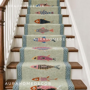 Puede incluir: Una alfombra de escalera color verde salvia con un patrón repetitivo de peces multicolores en tonos rosa, azul, naranja y negro. La alfombra tiene un borde geométrico azul verdoso y el texto AURAHOMEDECOR es visible en la superficie.