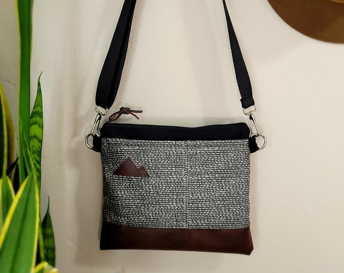 Small crossbody/Stormy print front = pocket/Gray & white/Black zipper/Black canvas/Black nylon adjustable strap/MT or Mountain patch