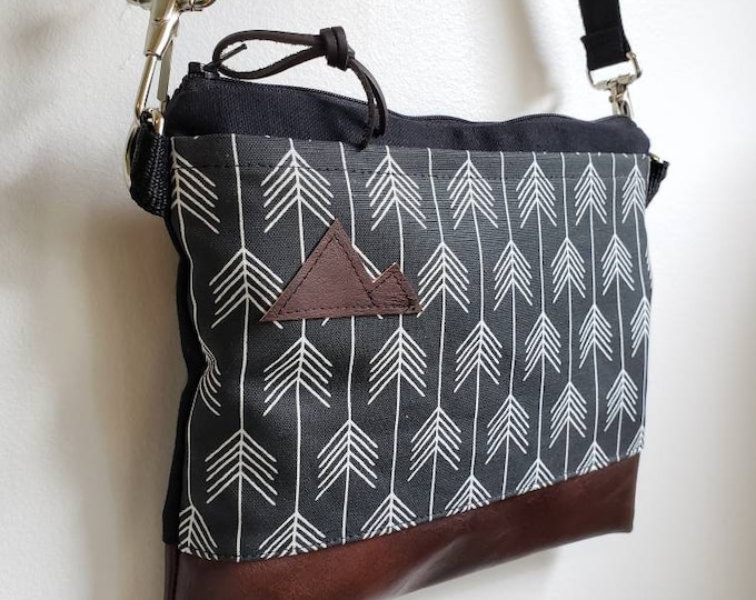 Small crossbody/True North print in black with white arrows = front pocket/Black zipper/Black canvas reverse/Black nylon adjustable strap