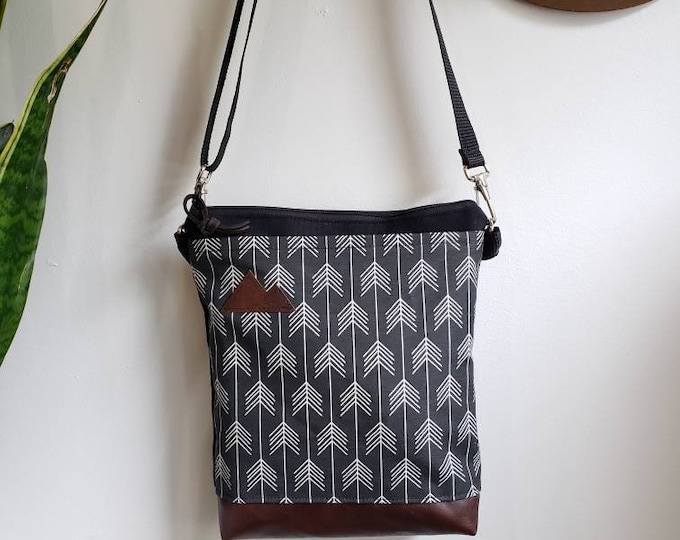 Medium crossbody/True North print in black with white arrows = front pocket/Black zipper/Black canvas reverse/Black nylon adjustable strap