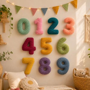 May include: A set of ten wall-mounted crochet numbers from zero to nine, each in a different solid color including mint, pink, teal, peach, magenta, yellow, lime, gold, purple, and blue, arranged in three rows against a plain wall.