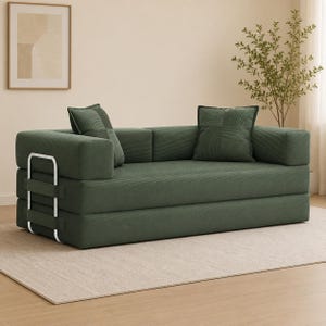 May include: A green modular sofa with two matching throw pillows. The sofa has a corduroy texture and a modern design. It features silver metal accents and a layered construction, suitable for a living room or guest space.