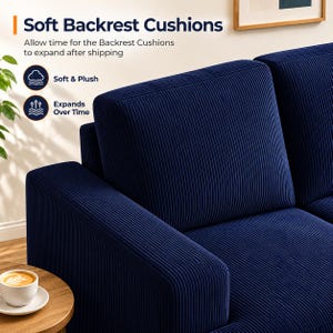 May include: Close-up of a navy blue corduroy sofa with soft backrest cushions. The cushions have vertical ridges and are labeled "Soft & Plush" and "Expands Over Time". A small wooden table with a cup of coffee is in the foreground.